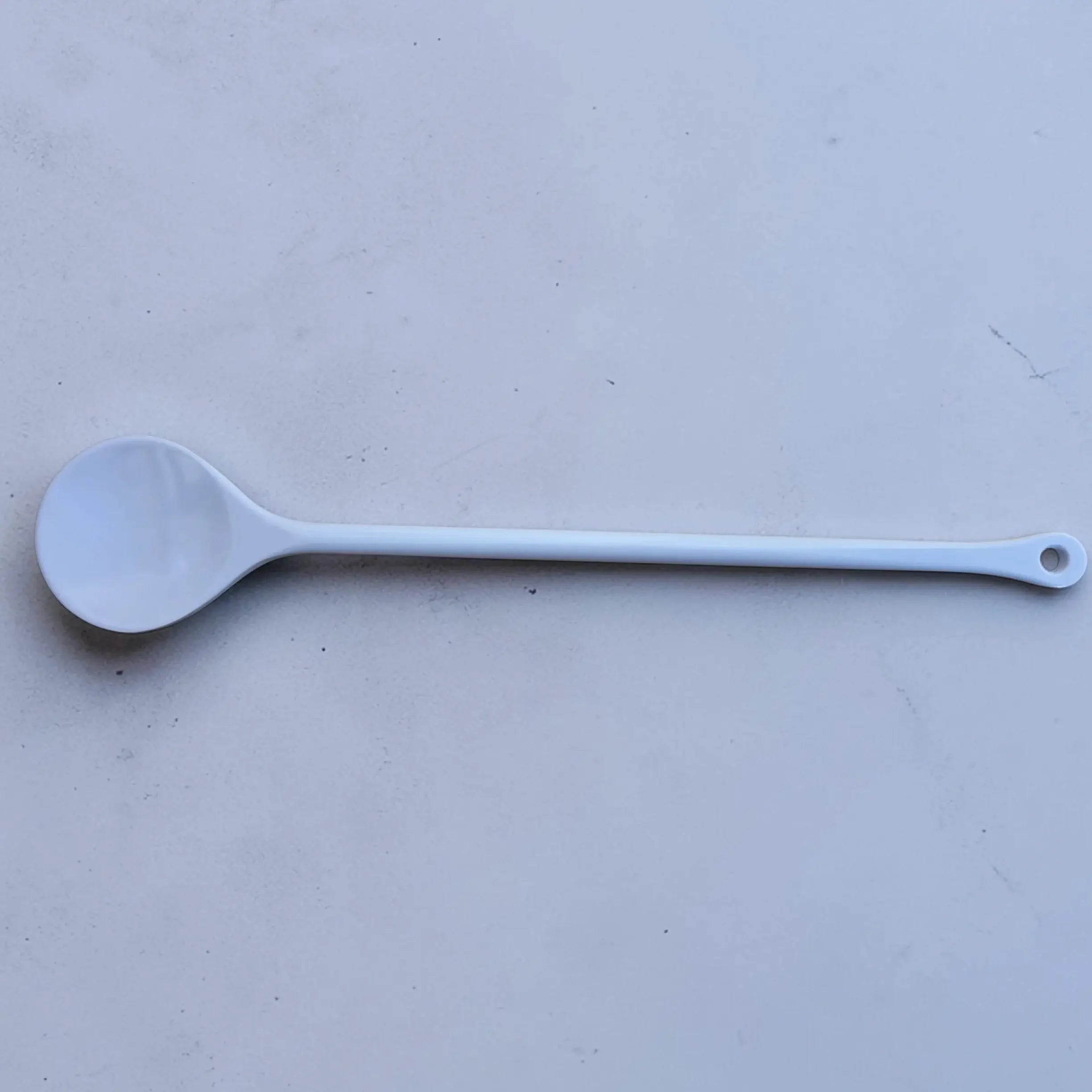 Short Plastic Stirring Spoon on a flat surface, showcasing its lightweight design and comfortable length of 31cm.