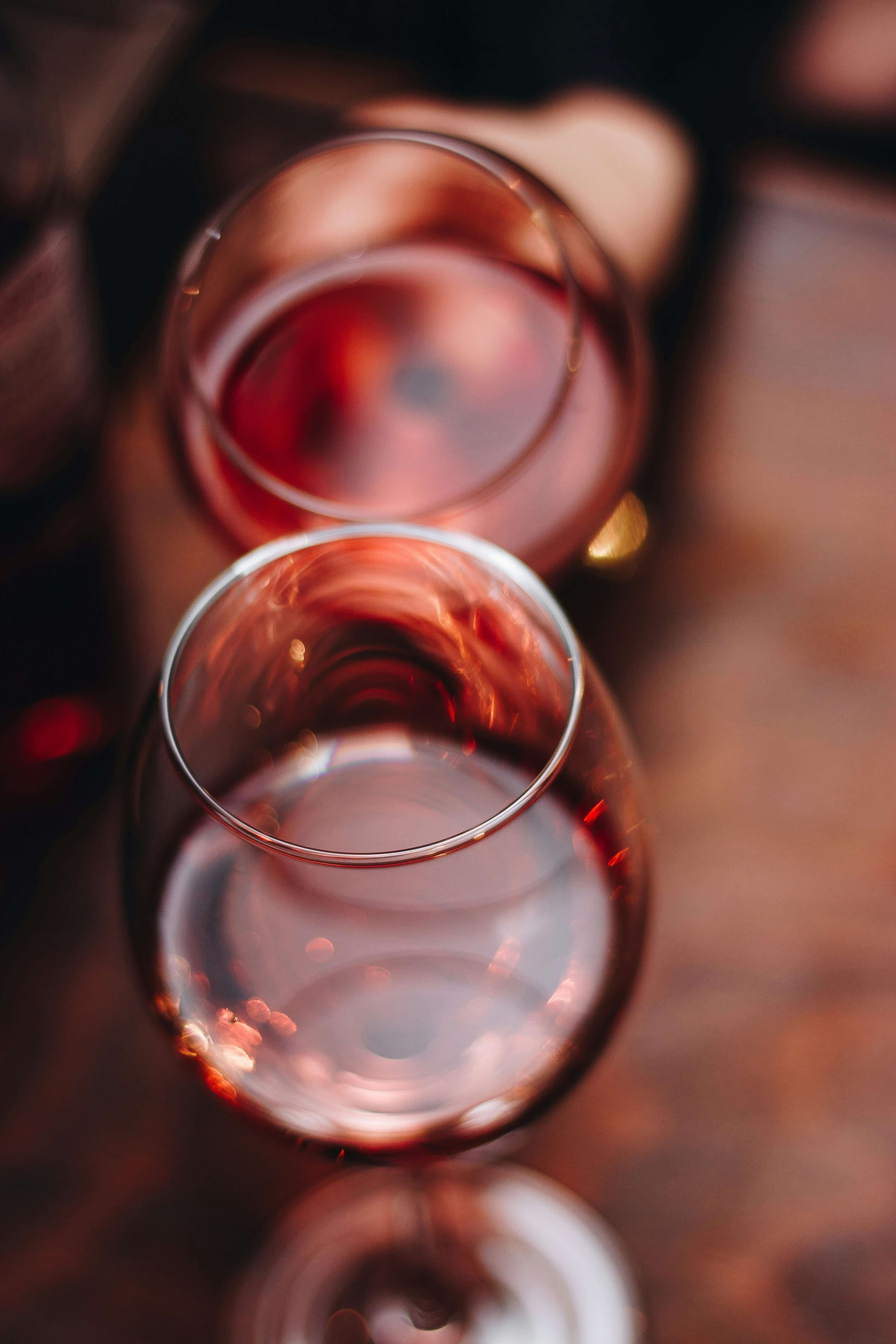 Close-up of two wine glasses filled with rosé wine on a wooden table, capturing a cozy dining atmosphere.