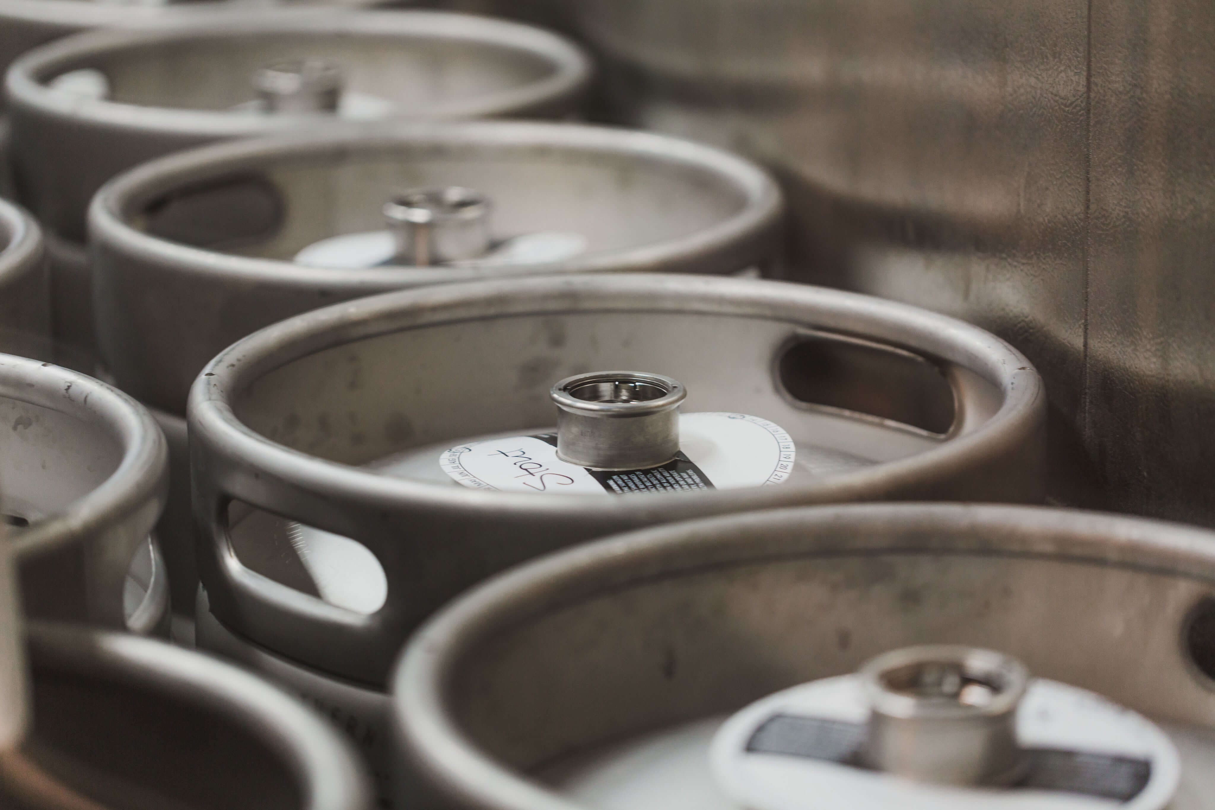 Metal beer kegs stacked in a brewery, showcasing the brewing industry's storage equipment.