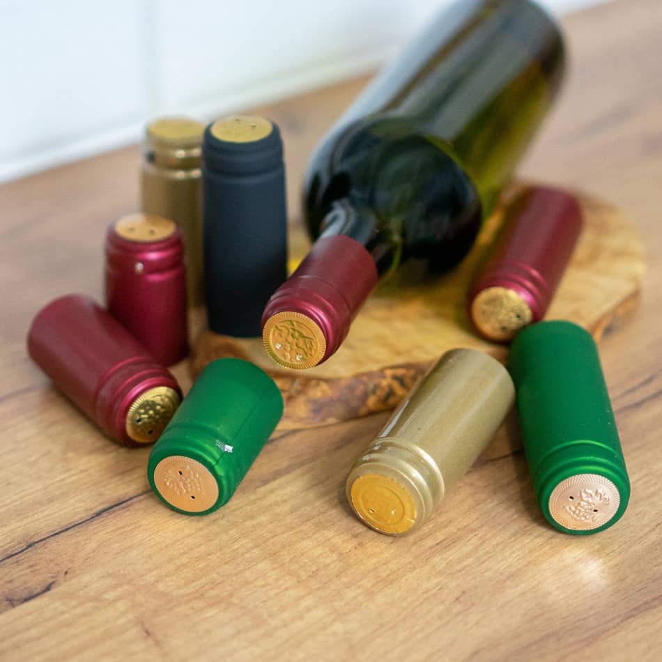 Multi Coloured Shrink Caps 100 Pack - Browin displayed next to a wine bottle on a wooden surface.
